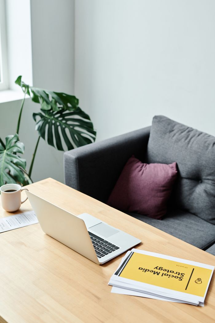 Cozy office setup with a laptop, papers, and greenery near a window.